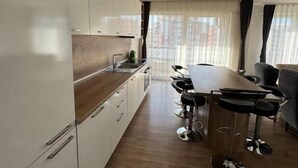 Una cocina moderna con armarios blancos, encimera de madera y comedor con mesa y taburetes de bar.