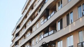 Un edificio residencial de varios pisos con balcones, ventanas y cielo despejado.