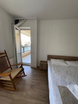 Une chambre à coucher avec un lit, un fauteuil à bascule et une vue sur l’extérieur.