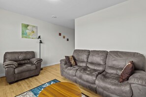 Ein Wohnzimmer mit zwei grauen Sofas, einer Stehlampe, einem runden Couchtisch und einem Bild an der Wand.