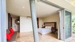 Ein modernes Schlafzimmer mit einem Bett, einem Nachttisch und einer Couch mit roten Kissen.