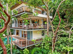 A multi-story building with balconies, a pool, and lush greenery. - OceanView Villa Private Pool & Jacuzzi in Amapas (Puerto Vallarta)