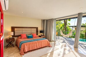 Een hotelkamer met een groot bed, uitzicht op een zwembad en een hangmat buiten.