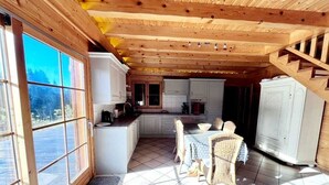 Interior de madera con comedor, cocina y ventanas amplias.
