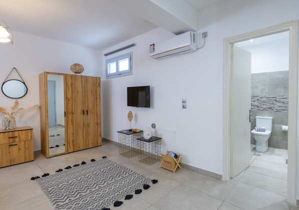 A bathroom with a toilet, a shower area, and a sink. - Begi Luxury Villas (Santorini)