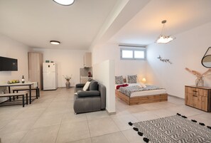 A modern apartment with a kitchen, dining area, and a bedroom with a bed and nightstand. - Begi Luxury Villas (Santorini)