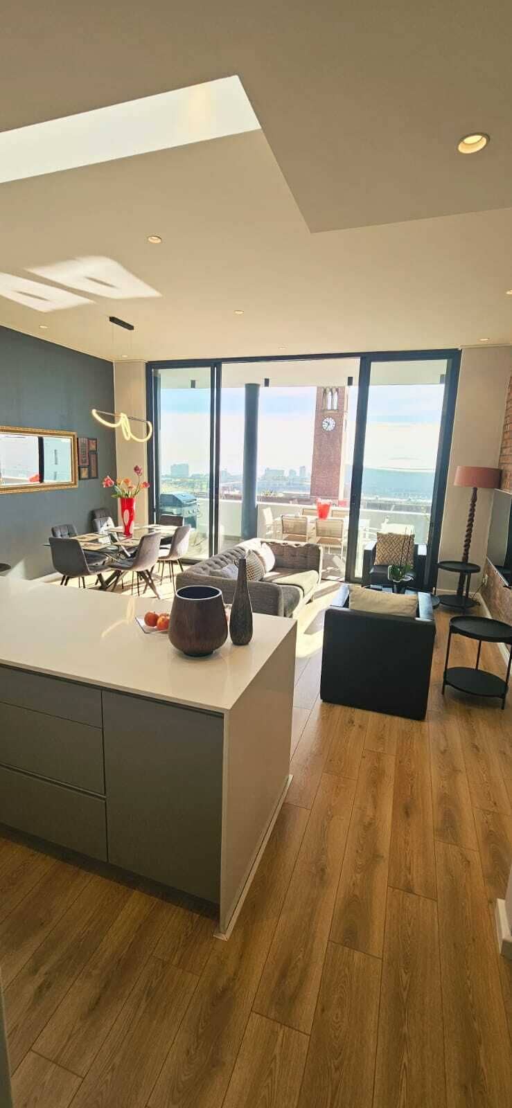 A modern kitchen with a large island, dining area, and a view of the city.