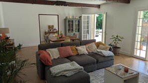 A living room with a sofa, a coffee table, and a dining area with a table and chairs. - House with swimming pool in the heart of the Parc de la Sainte-Baume (La Roquebrussanne)