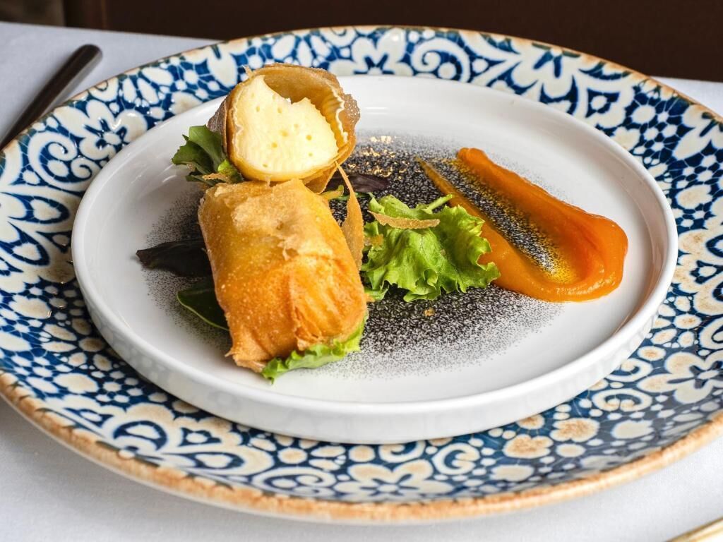Un plato con comida empanizada, lechuga y zanahoria sobre un plato decorativo.