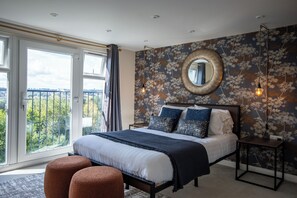 Ein Schlafzimmer mit einem großen Bett, einem runden Spiegel und Blick aus dem Fenster.