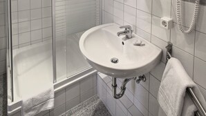 Un baño moderno con cabina de ducha de vidrio, un lavabo blanco y un espejo con iluminación.