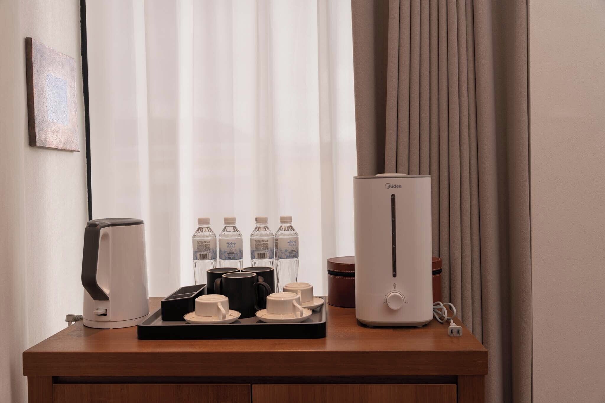 A hotel room with a coffee maker, tea maker, and a water dispenser on a wooden table.