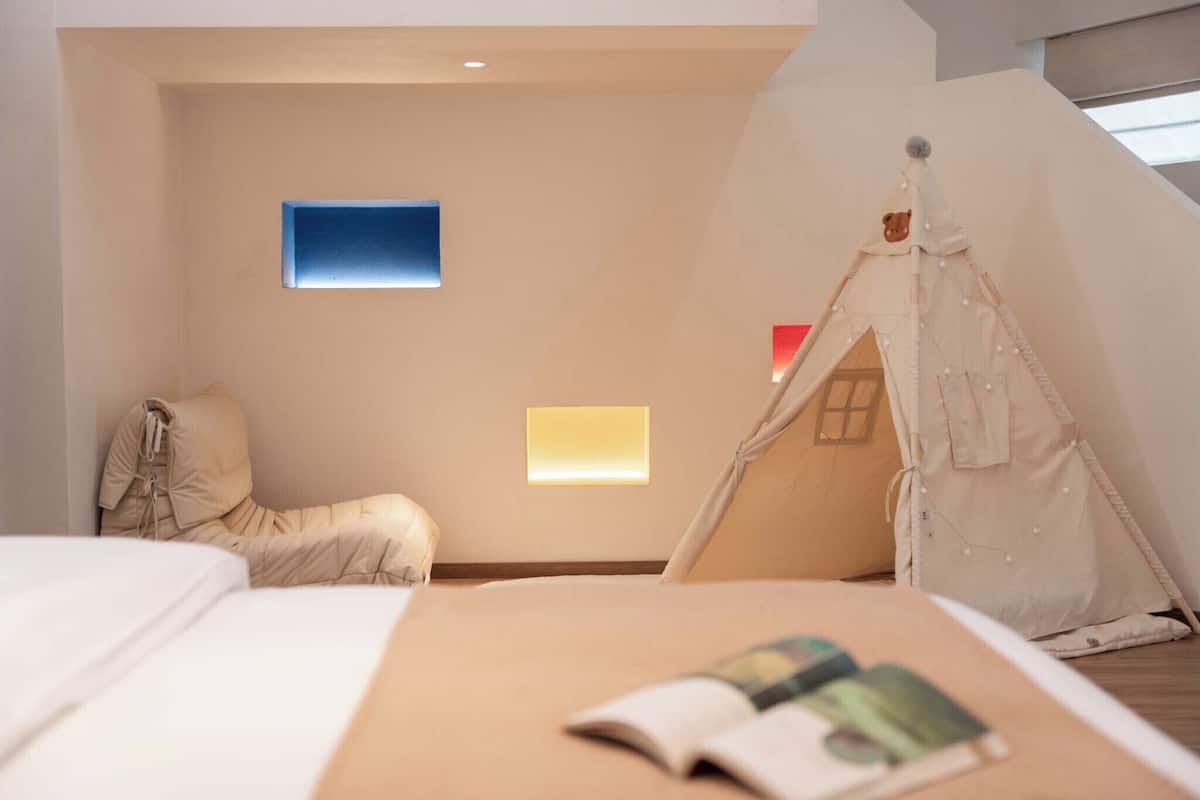 A bedroom with a bed, a tent-like structure, a chair, and two wall-mounted lights.