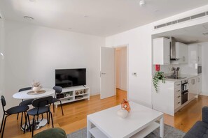 Ein modernes Wohnzimmer mit Essbereich, Fernseher und Küche.