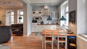 Una cucina moderna con mobili bianchi, un tavolo da pranzo in legno e una lampada a sospensione blu.