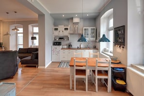 A modern kitchen with white cabinets, a wooden dining table, and a blue pendant light. - RentPlanet - Apartament Mickiewicza (Karpacz)