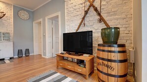 Un soggiorno con televisore, botte di legno e parete in mattoni.