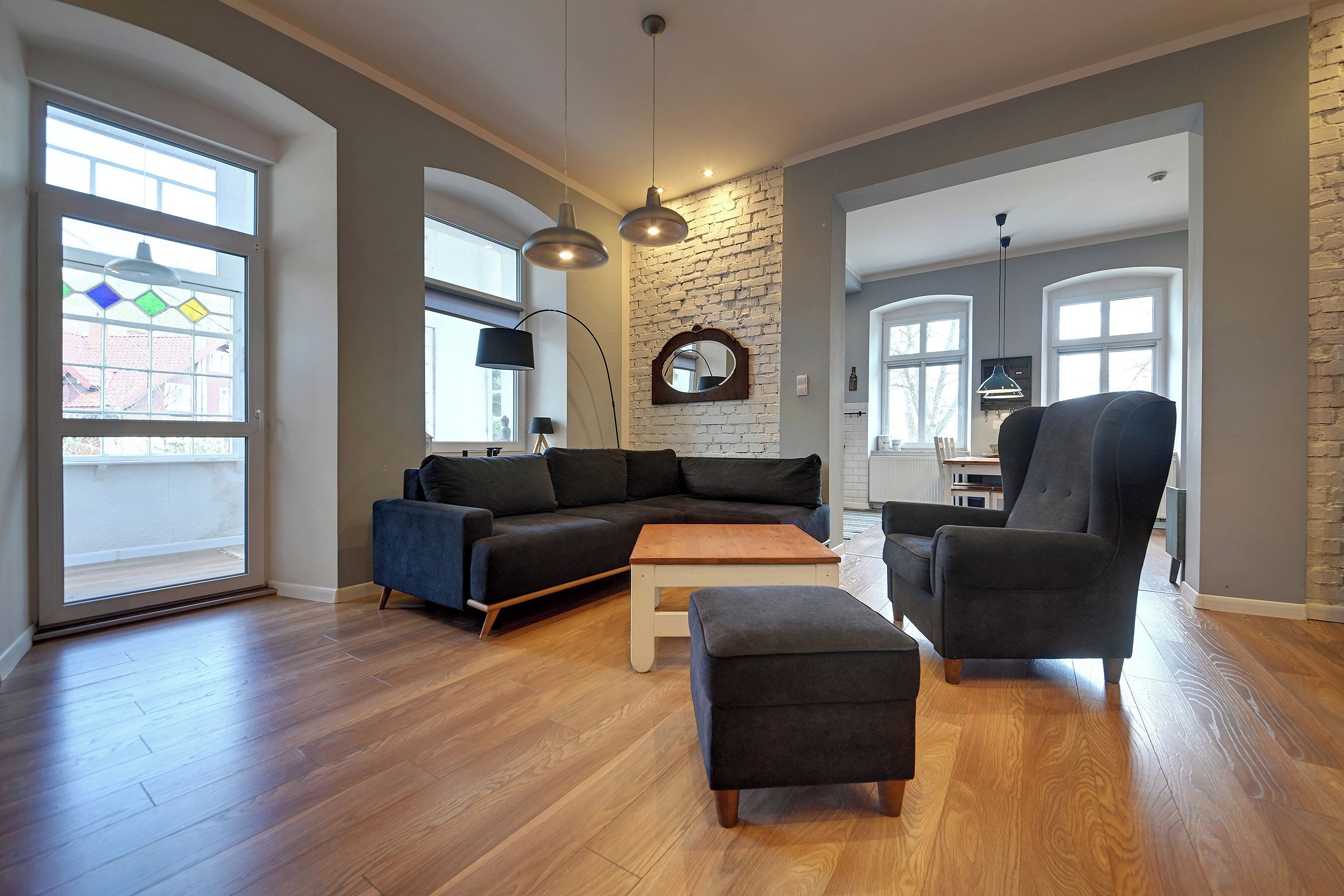 A spacious living room with a sectional sofa, a coffee table, and a dark armchair.