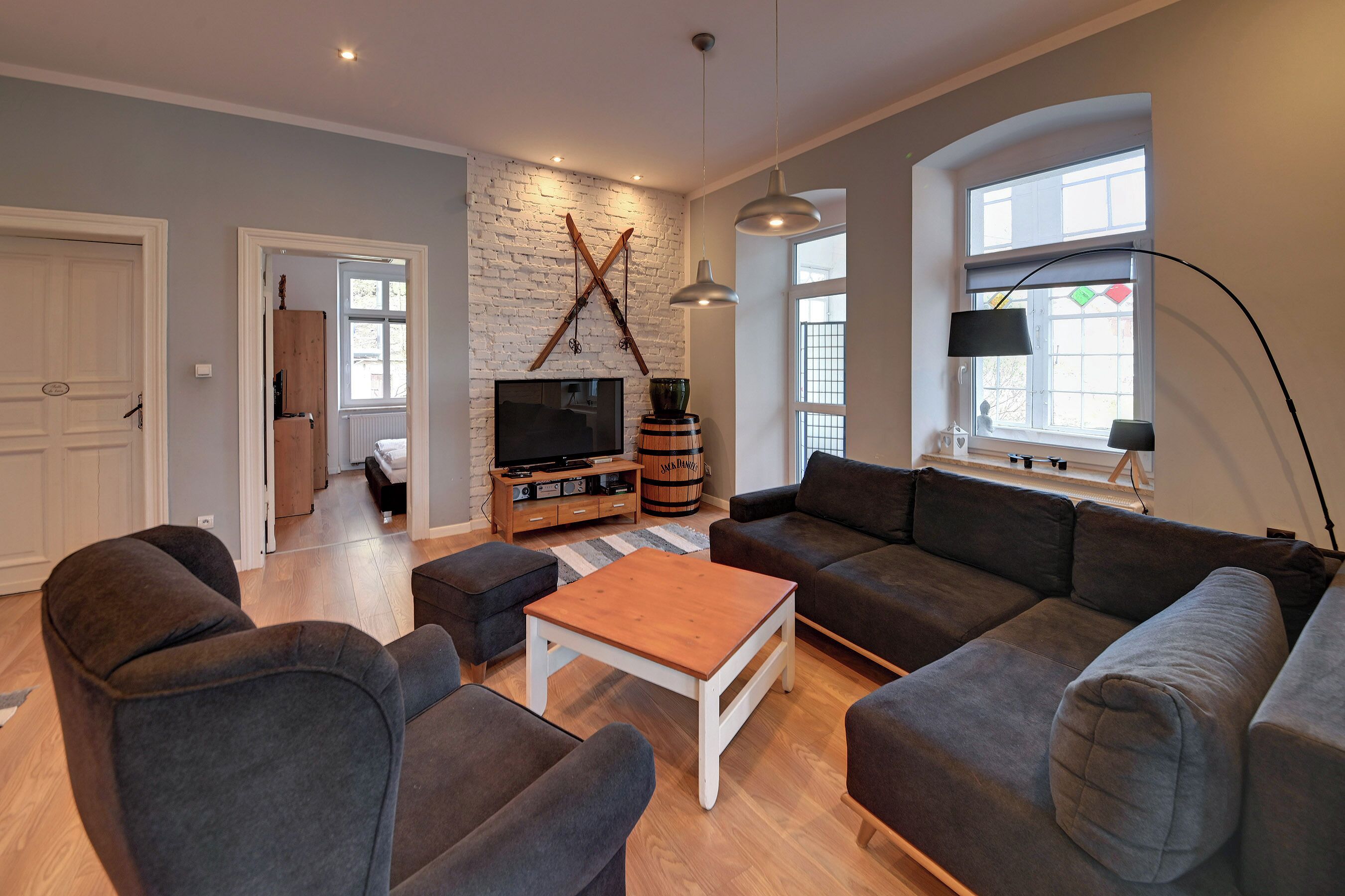 A living room with a sofa, armchairs, a coffee table, a TV, and a fireplace.