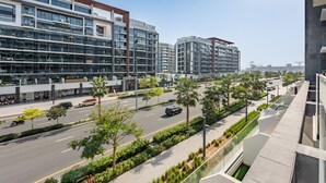 Ein modernes Mehrstöckengebäude mit großen Fenstern, einer Straße mit Autos und Palmen.