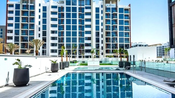 Ein modernes Hotel mit Pool, mehreren Etagen und blauem Himmel.