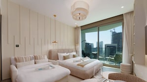 A modern hotel room with two beds, a dining area, and a large window with a city view.