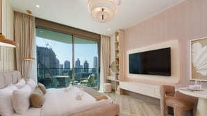 A modern hotel room with a large bed, a TV, a dining area, and a view of the cityscape.