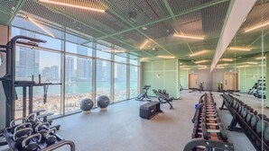 A gym with exercise equipment, large windows, and a city view.
