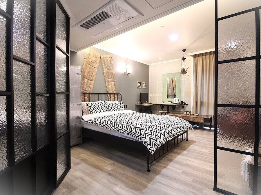 Un dormitorio moderno con una cama, un escritorio y un espejo.