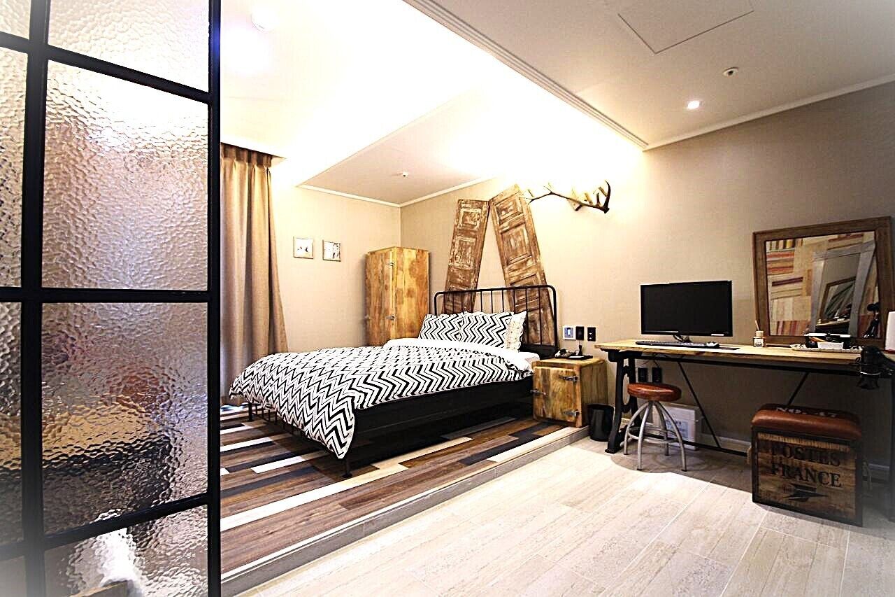 Una camera da letto moderna con un letto, una scrivania, una sedia e uno specchio.