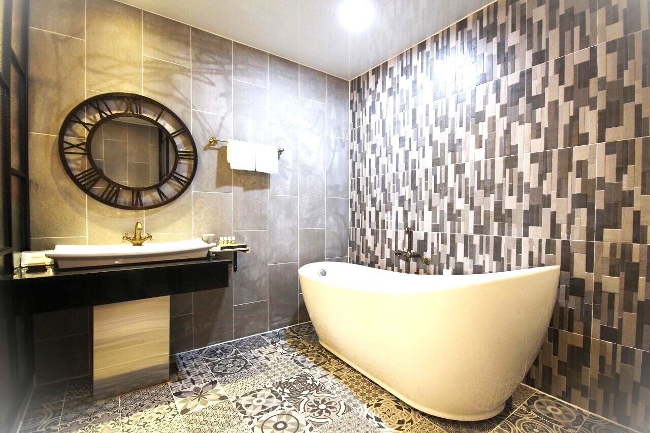 Un baño moderno con una bañera independiente, un espejo redondo y un tocador con lavamanos.