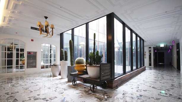 A spacious lobby with a modern design, featuring a large window, a cactus display, and a chandelier. - Heritage Hotel (Changwon)