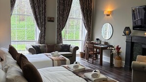 A hotel room with two beds, a dining area, a TV, and a fireplace.