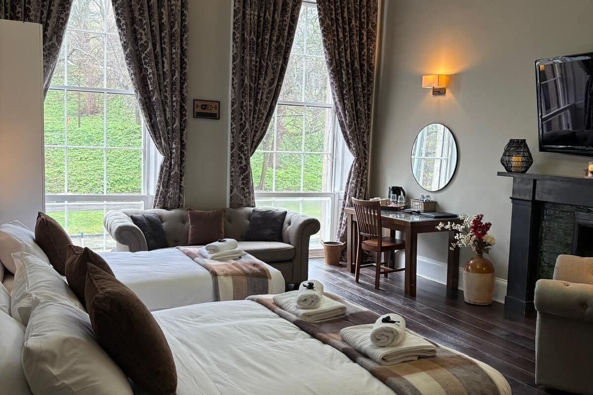 A hotel room with two beds, a dining area, a TV, and a fireplace.