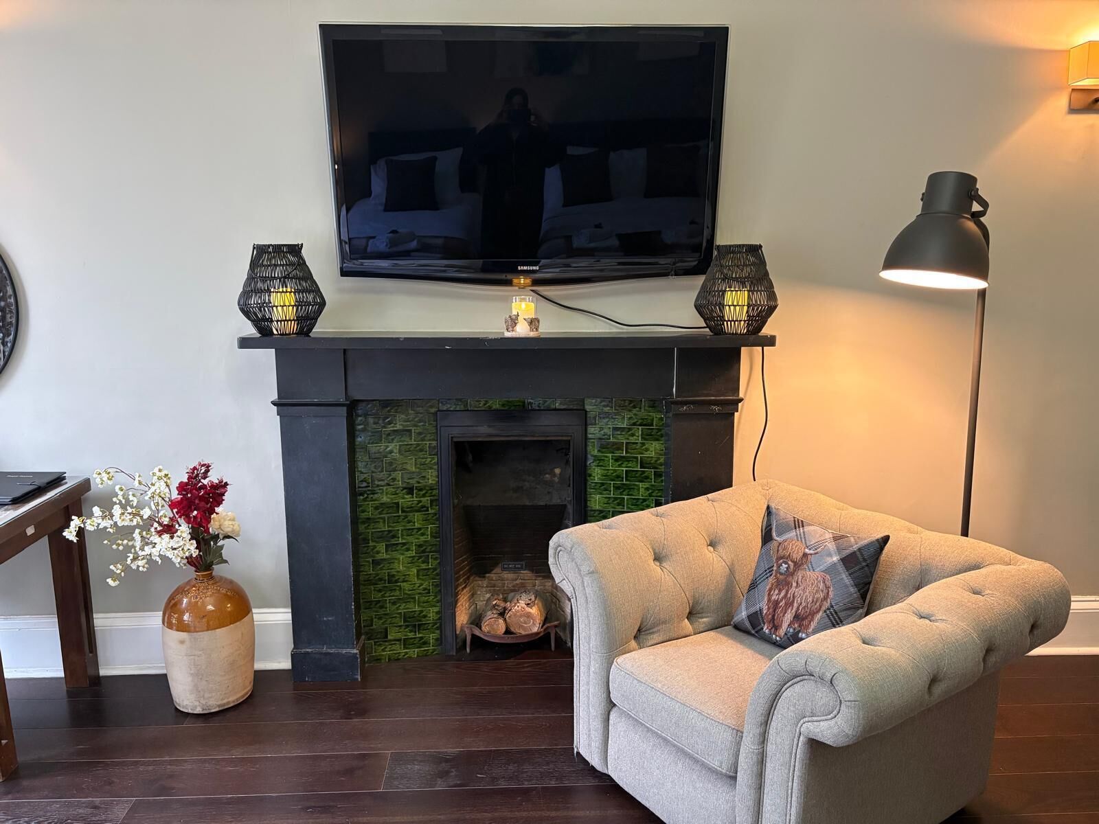 Un salon doté d’une cheminée, d’un téléviseur fixé au-dessus et d’un canapé agrémenté de coussins décoratifs.