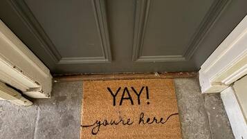 A doormat with the words 'YAY! you're here' on a textured surface.