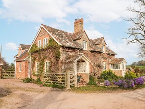 A traditional stone house with a wooden gate, surrounded by a gravel driveway and a flower bed. - Tuxwell Lodge (Bridgwater)