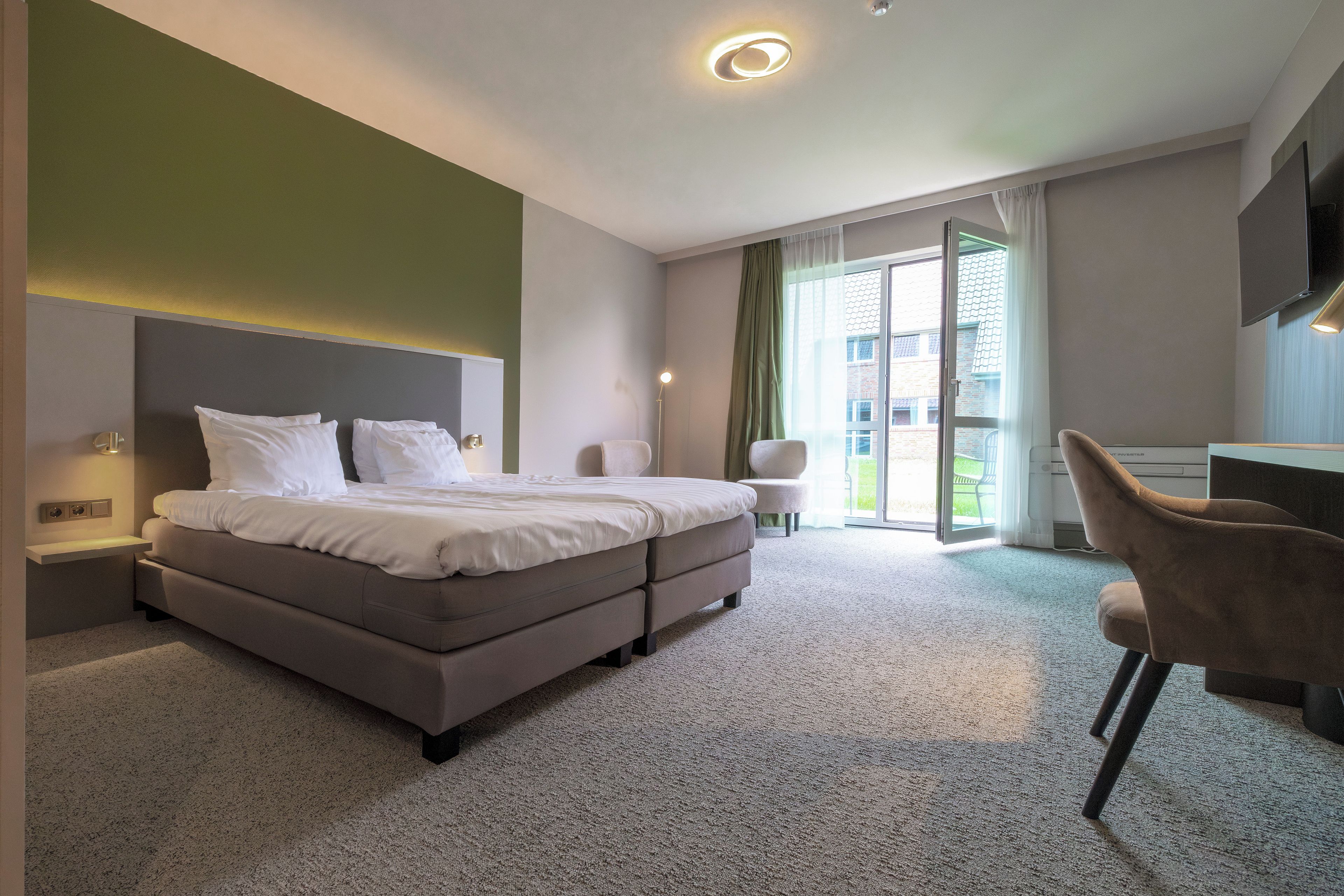 Een moderne hotelkamer met een bed, een bureau en een stoel.