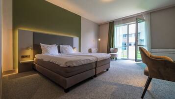 Una camera d'albergo con un letto, una sedia, una scrivania e vista sull'esterno.