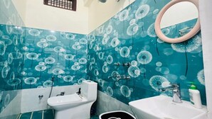 A bathroom with a toilet, bidet, sink, and a trash bin. - Vandana Palace (Ayodhya)