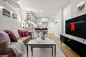 Ein modernes Wohnzimmer mit einer Couch, einem Couchtisch und einem Flachbildfernseher.