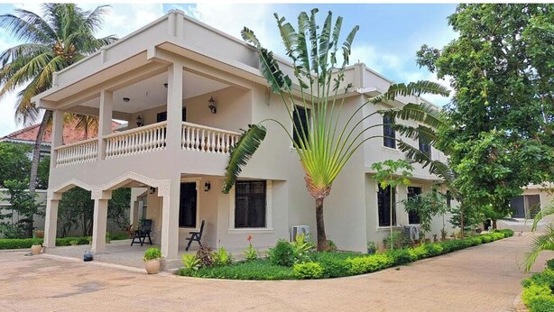 A two-story building with a balcony, potted plants, and a pathway leading to the entrance. - Mbweni Zanzibar Lux House (Zanzibar Town)