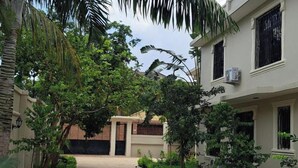A narrow pathway flanked by lush greenery and buildings with barred windows. - Mbweni Zanzibar Lux House (Zanzibar Town)