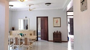 A dining area with a table and chairs, a ceiling fan, a chandelier, and a door leading to another room. - Mbweni Zanzibar Lux House (Zanzibar Town)