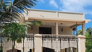 A two-story building with a balcony, a gated entrance, and a clear sky. - Mbweni Zanzibar Lux House (Zanzibar Town)