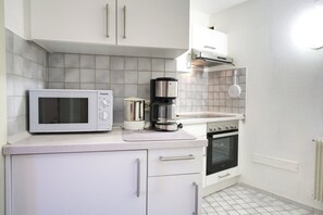 A kitchen with a microwave, coffee maker, and oven. - Apartment - 44m2 - with DreiWeltenCard free entry to the thermal spa, quiet & central (Bad Dürrheim)