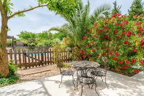 Une terrasse avec une table et des chaises rondes en métal, entourée d’une plateforme en bois et d’une clôture en bois.