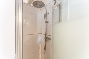 Une douche équipée d’un pommeau de douche à main et d’un robinet mural.