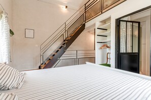 Une chambre à coucher comprenant un lit, un escalier, une armoire et une porte donnant sur une autre pièce.