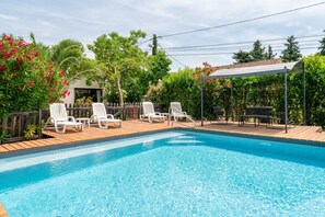 A swimming pool with lounge chairs, a wooden deck, and a pergola. - Cottage 'Gîte Chez Augustine' with Wi-Fi and Air Conditioning (Sarrians)